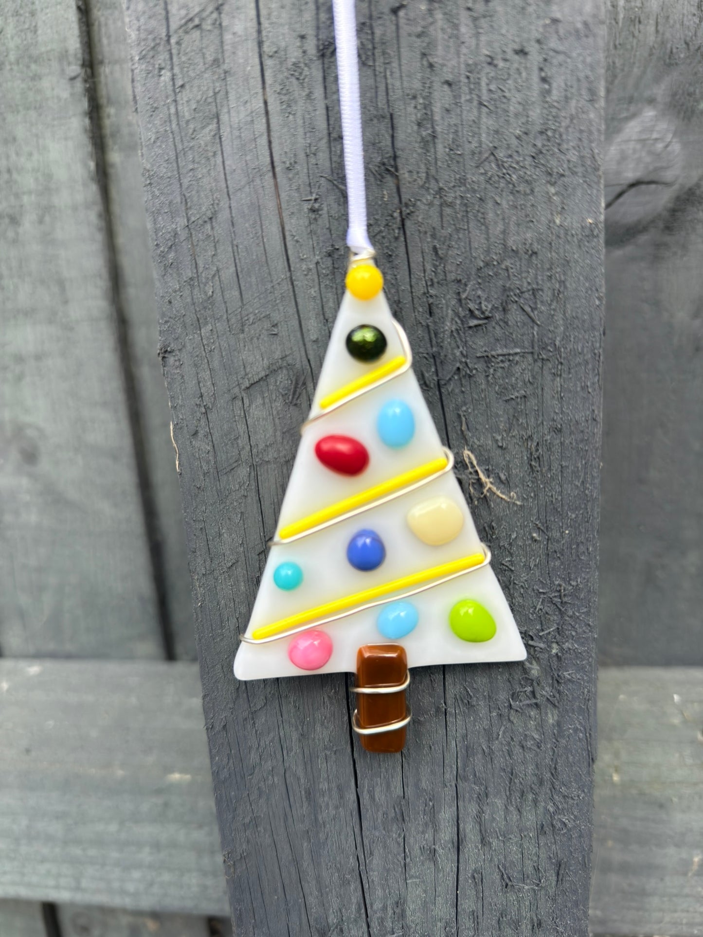 Colorful triangular ornament with beads hanging on a wooden surface
