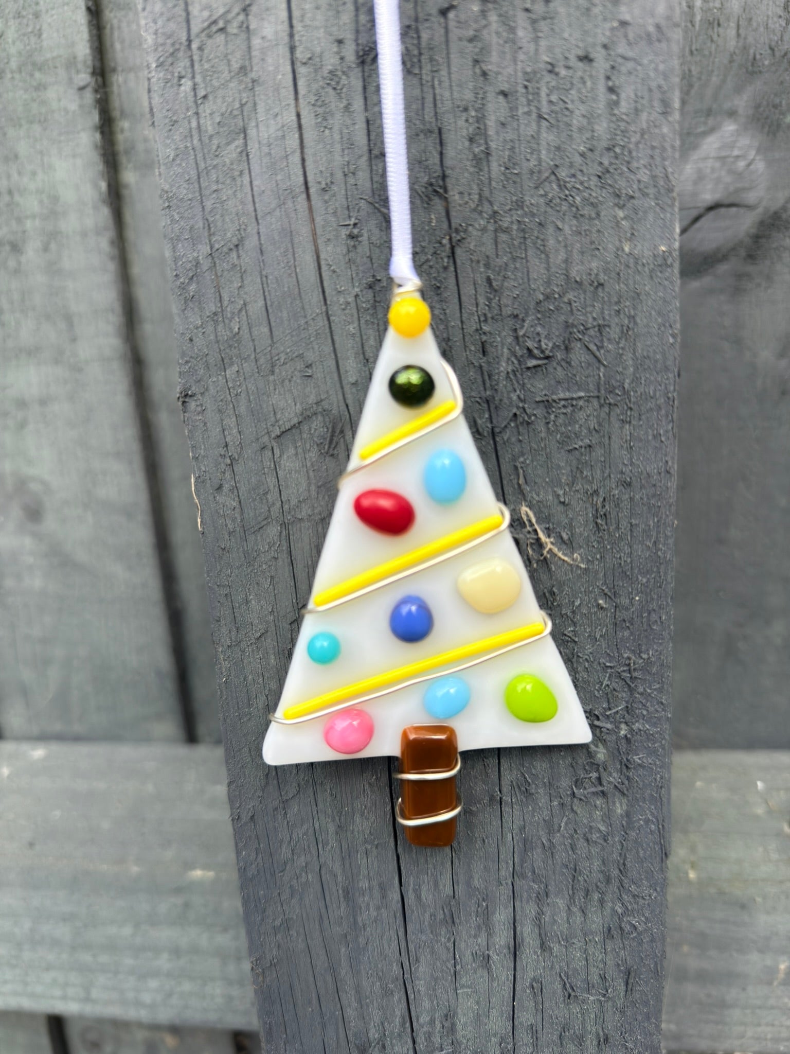Colorful triangular ornament with beads hanging on a wooden surface